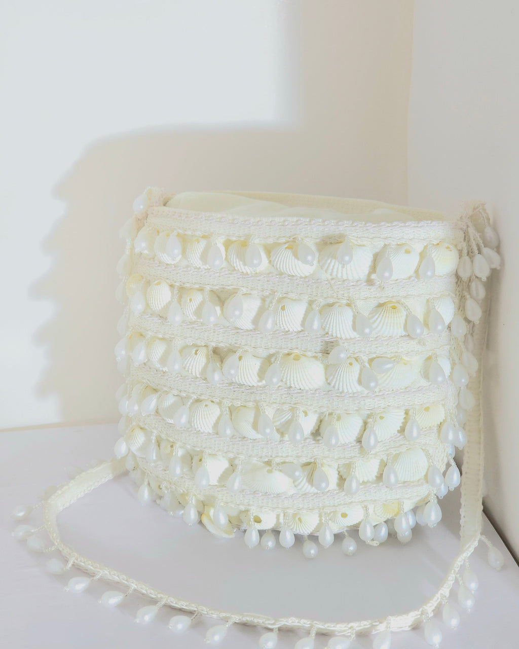White textured bag with pearl embellishments on a white background