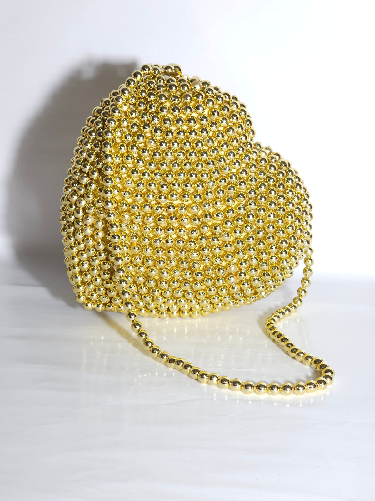 Gold heart-shaped handbag with chain strap on a white background